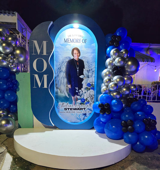 Memorial display for a 'Mom' with blue and silver balloons and a plaque.