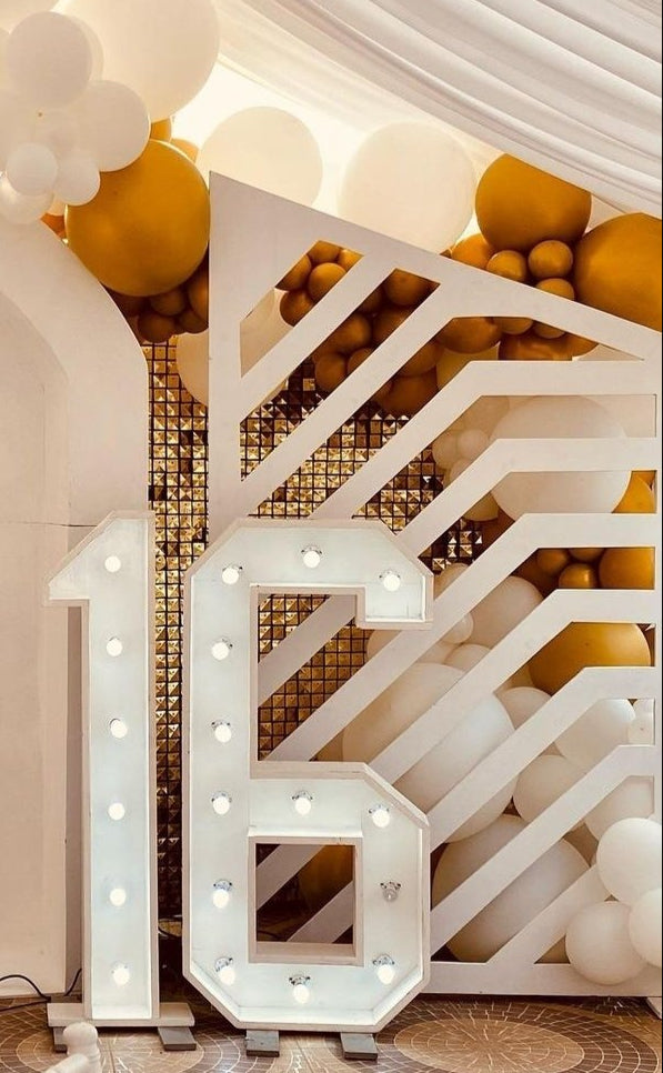 Decorative setup with 'Caterina Sweet' cake, balloons, and illuminated number '16' at a celebration.